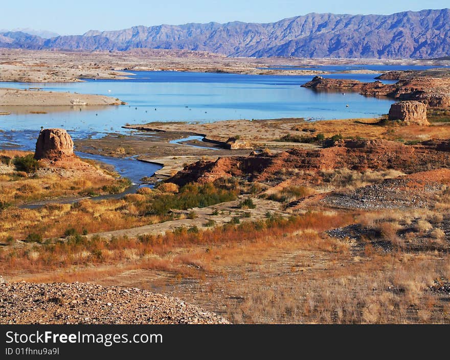 Long view of the rocky shore of a lake with a low mountain range in the background. Long view of the rocky shore of a lake with a low mountain range in the background