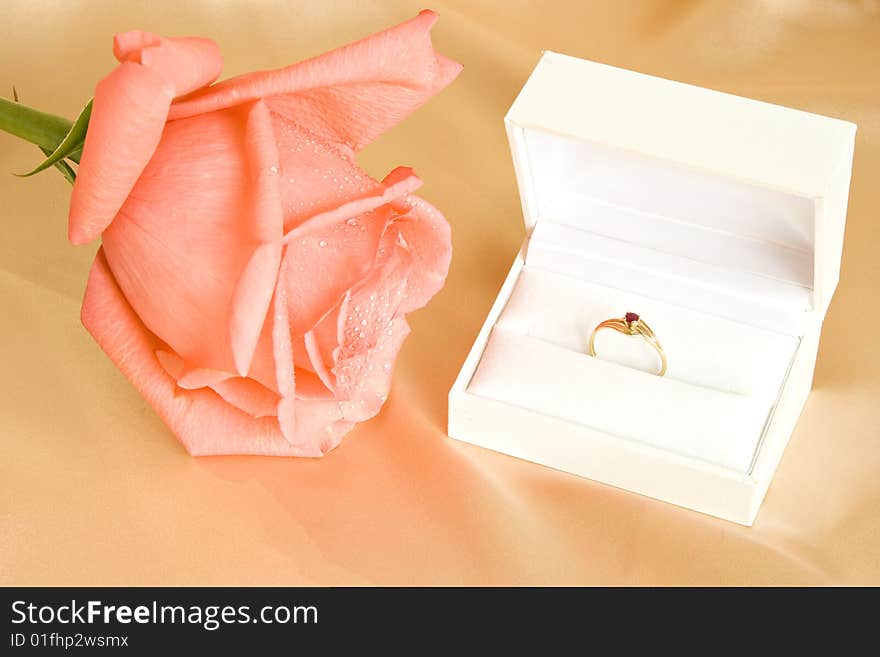 Beautiful rose and golden ring in gift box on silk backgroung. Beautiful rose and golden ring in gift box on silk backgroung