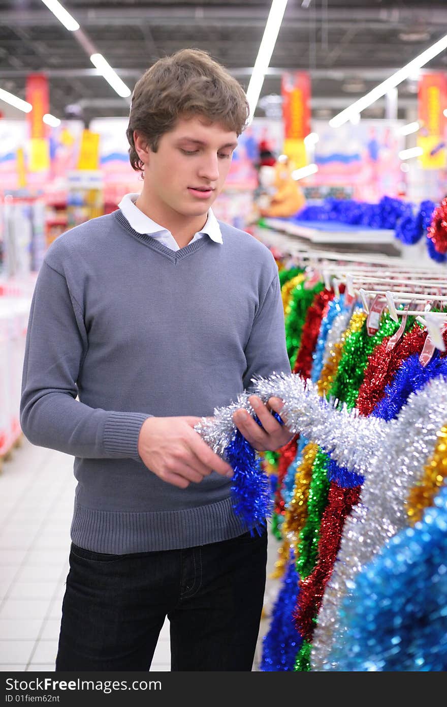 Young man chooses Christmas-tree decoration