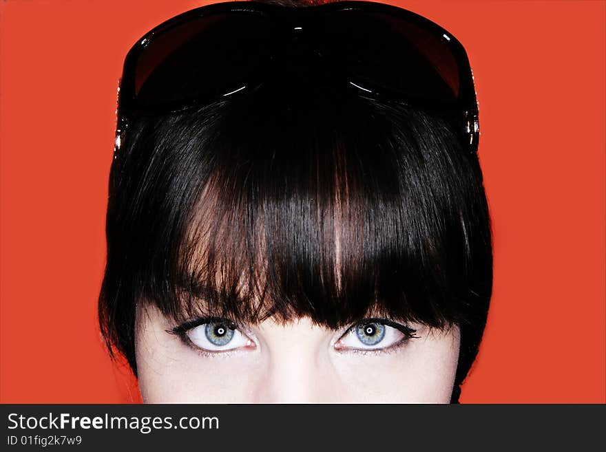 Attractive brunette with sunglasses close up against an orange background