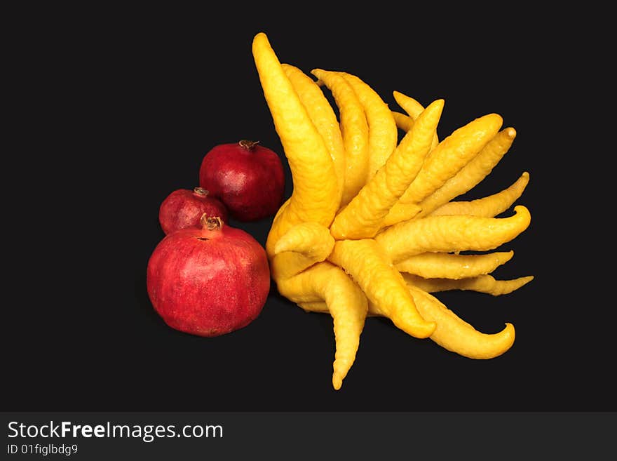 Pomegranate  and  Buddha Hand Lemon on black background.