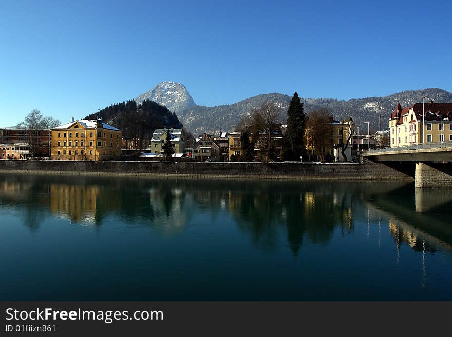 Inn River in Kufstein City , Tirol, Austria .
Buildings Mountains and blue sky is reflecting in blue water.