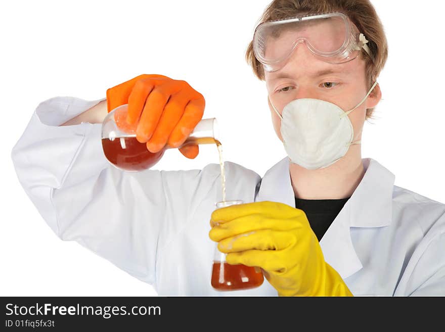 Scientist in respirator and rubber gloves pours brown liquid from one flask in another. Scientist in respirator and rubber gloves pours brown liquid from one flask in another