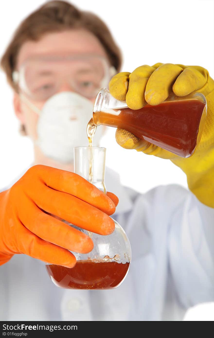 Scientist in respirator and rubber gloves pours  brown liquid from one flask in another. Scientist in respirator and rubber gloves pours  brown liquid from one flask in another