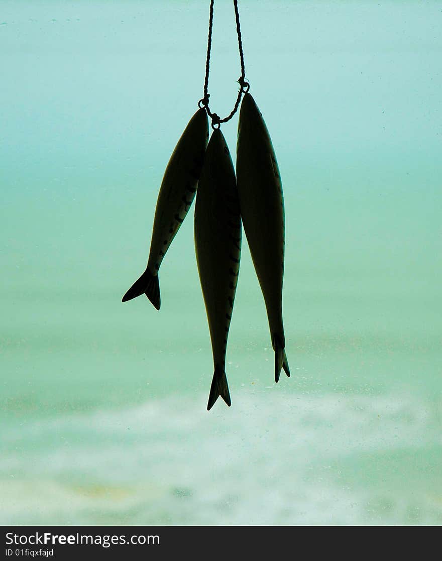 Wooden carved fish, hanging in a window overlooking the sea. Wooden carved fish, hanging in a window overlooking the sea