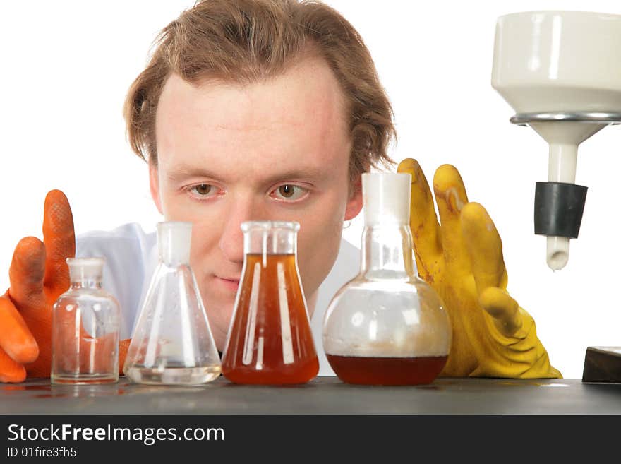 Chemist looks on flasks with liquids on white