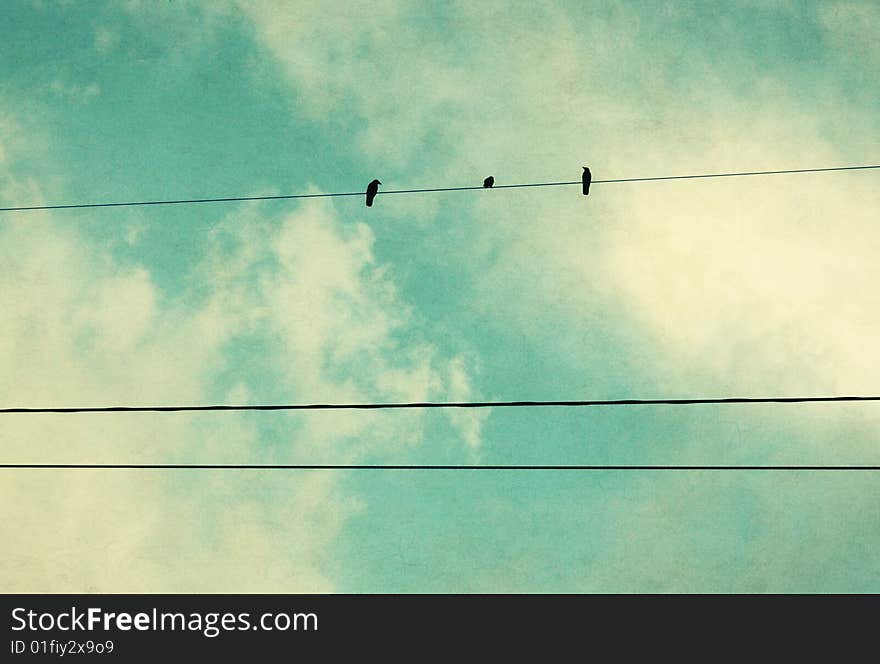 Three birds on a wire in a blue sky. Three birds on a wire in a blue sky