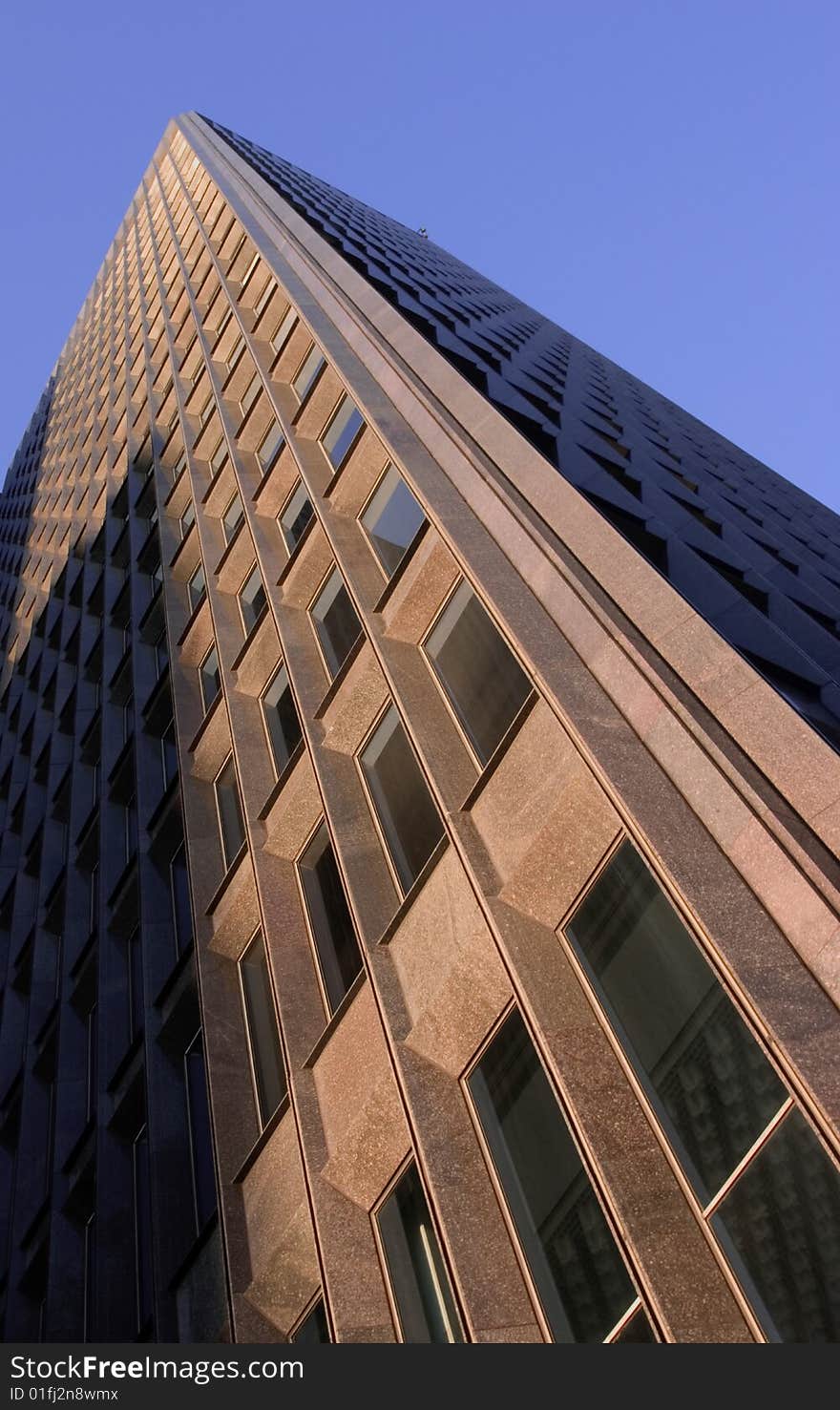 Exterior of a modern commercial building showing lots of windows and a blue sky above. Exterior of a modern commercial building showing lots of windows and a blue sky above.