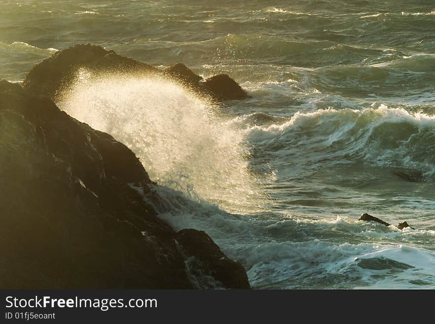 Evening ocean waves in the dark rocks