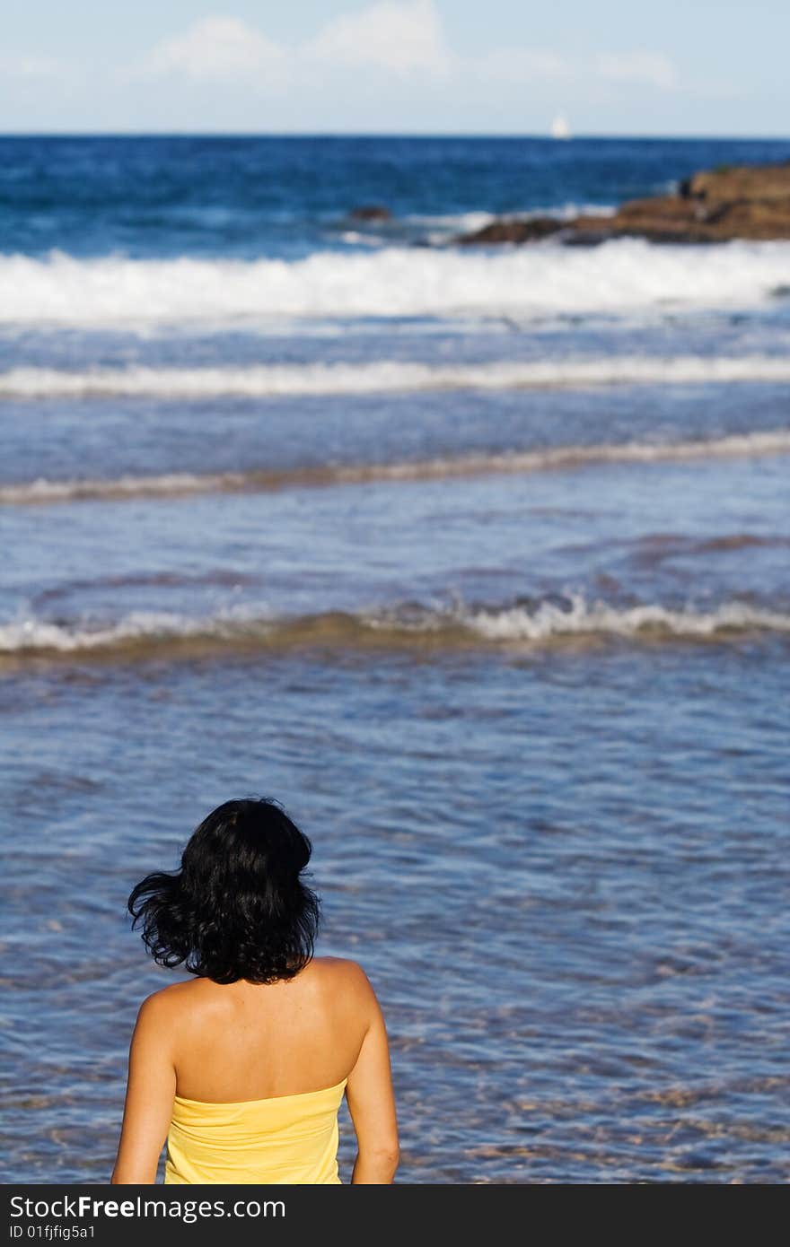 Back view of young woman standing at water's edge on Manly, Sydney. Gazing at the ocean. Back view of young woman standing at water's edge on Manly, Sydney. Gazing at the ocean.