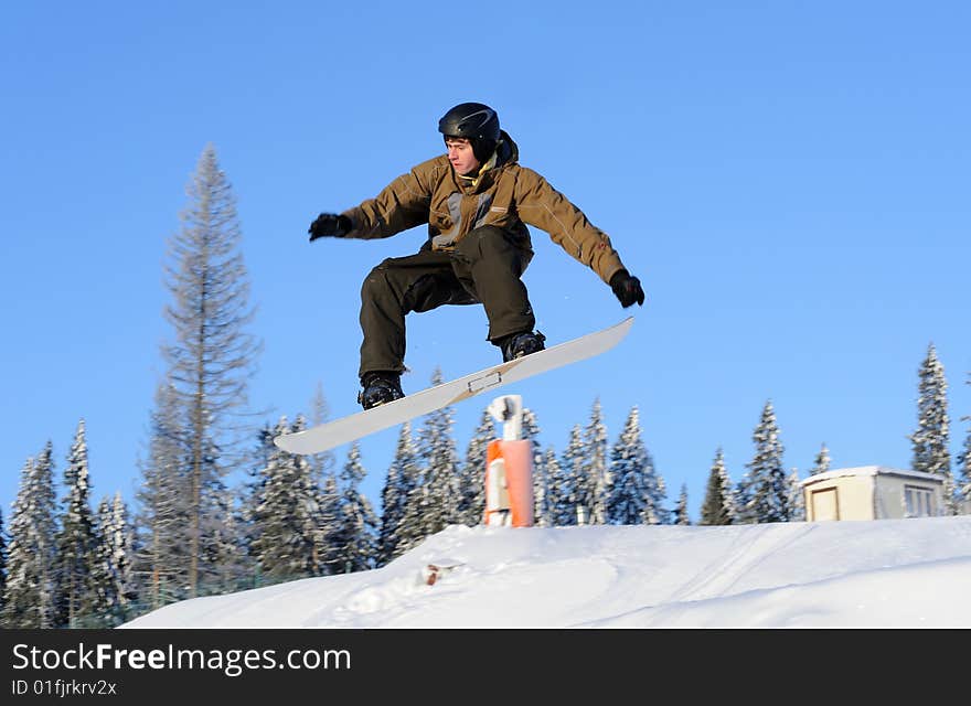 Photo of a young male snowboarder jumping against a blue sky