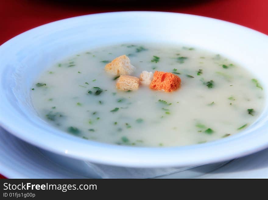 White plate with soup on a red cloth