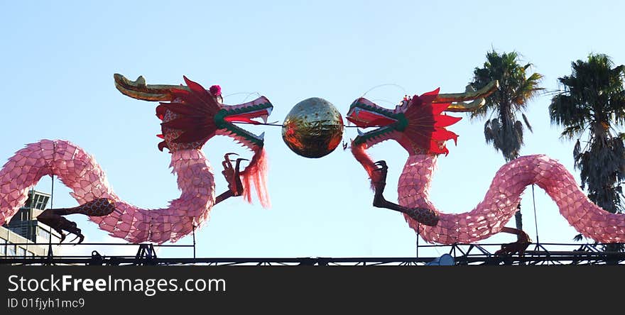 Scenic photo of a pair of chinese dragons with  office buildings in the background somewhere in New Zealand