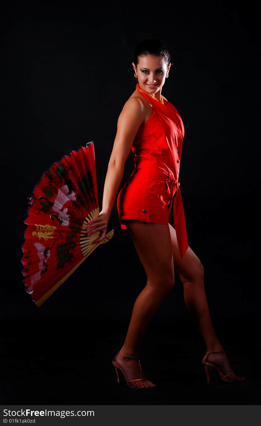 Beautiful brunet woman in red clothes with fan at black background. Beautiful brunet woman in red clothes with fan at black background