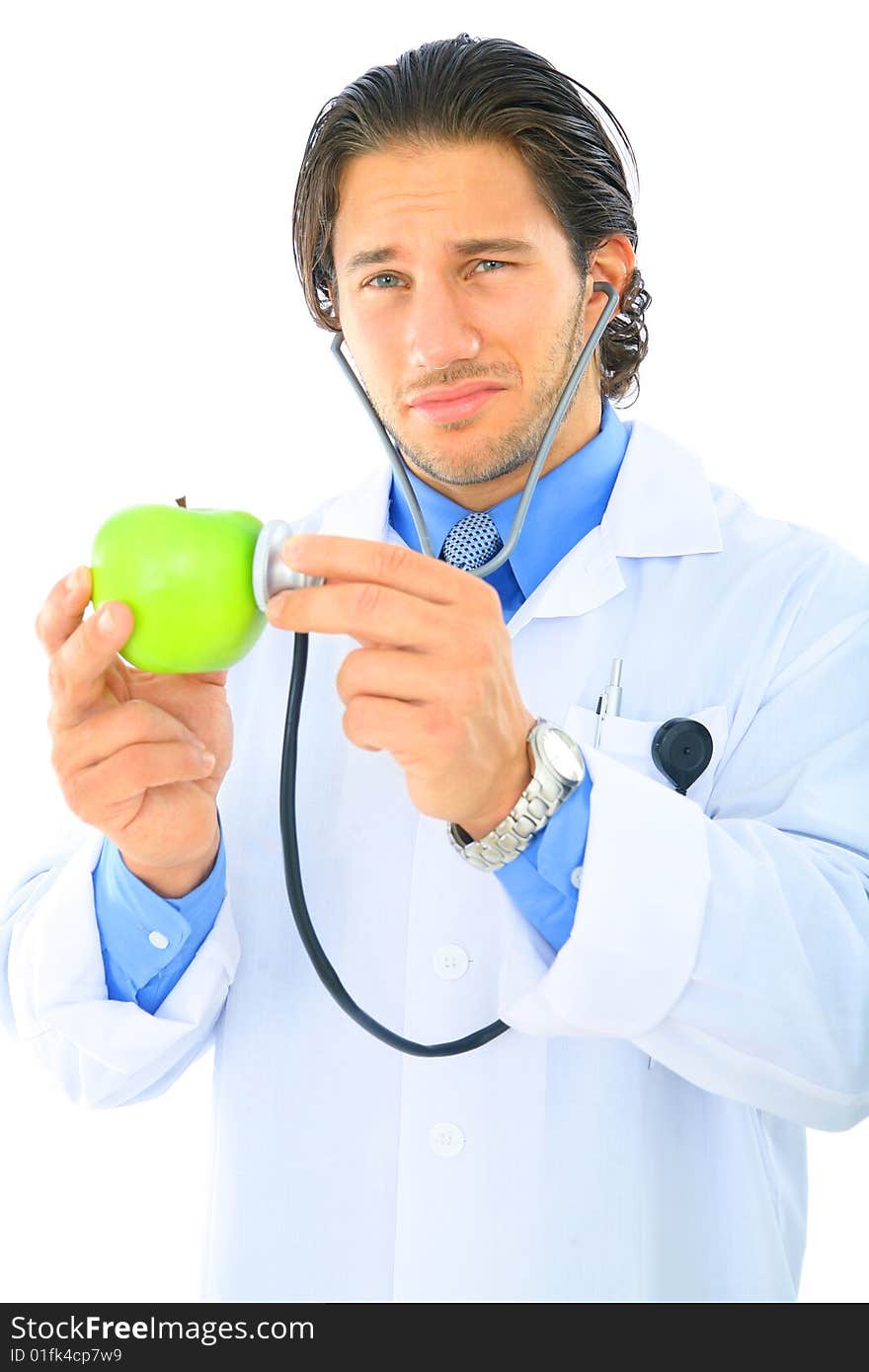 Young doctor showing unhappy expression checking on green apple. Young doctor showing unhappy expression checking on green apple