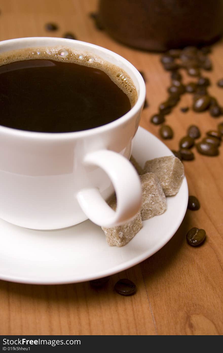 Cup of coffee, sugar and beans on wooden table