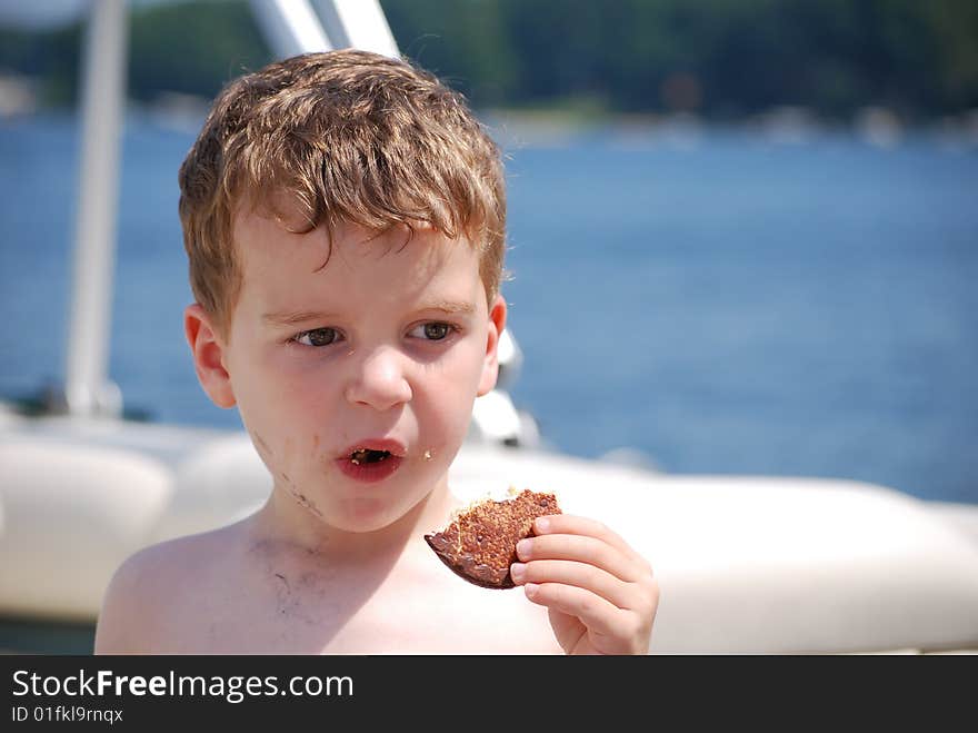 A little boy makes a mess with his cookie on the boat. A little boy makes a mess with his cookie on the boat