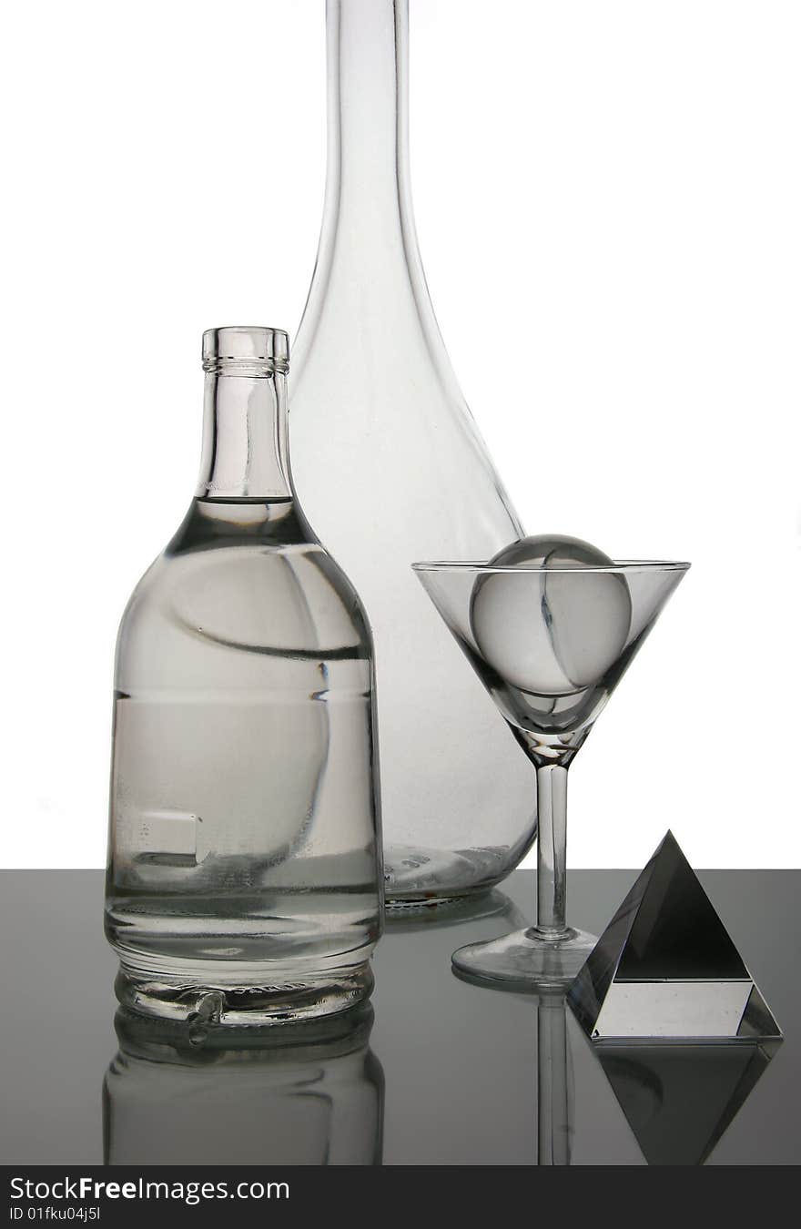 Still life with a glass and bottles on a white background