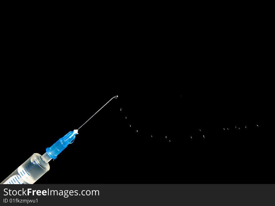 Syringe and drops of medicine on a black background