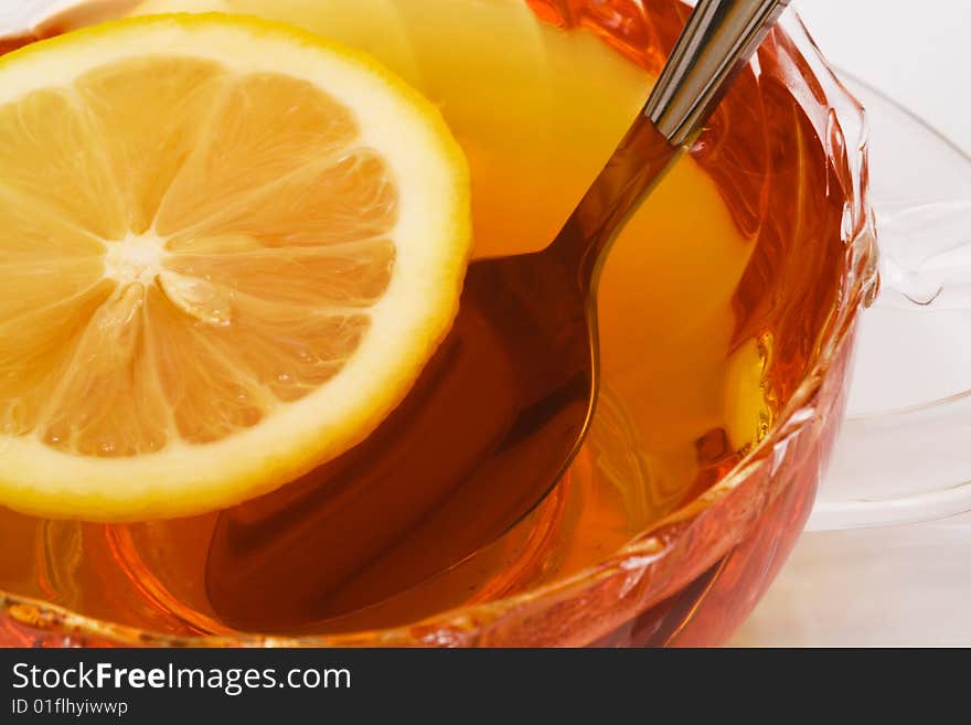 Glass cup with tea and a lemon on a white background