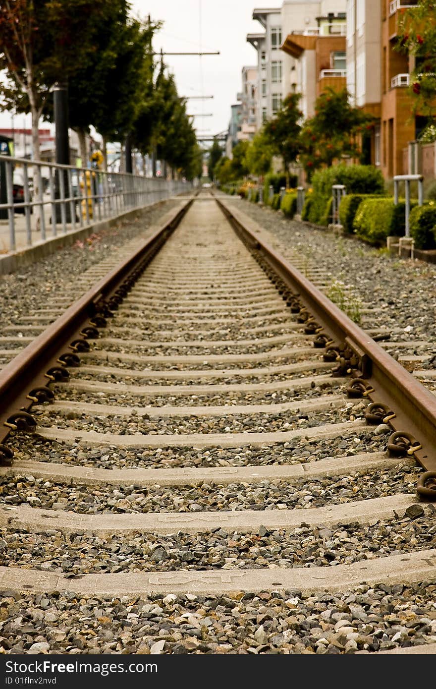 Railroad tracks running straight alongside a city street. Railroad tracks running straight alongside a city street