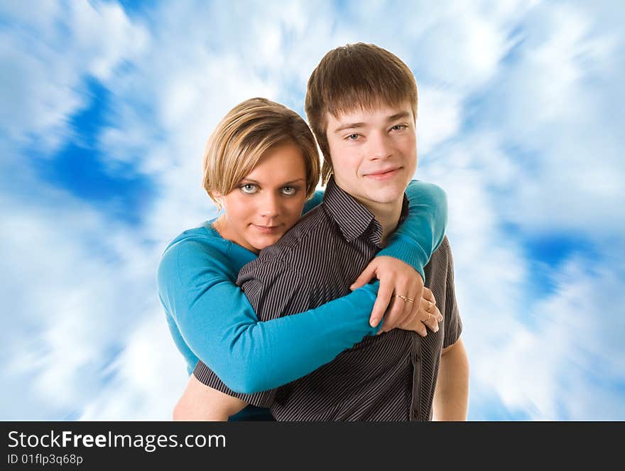 Young couple hugging (blue sky background)