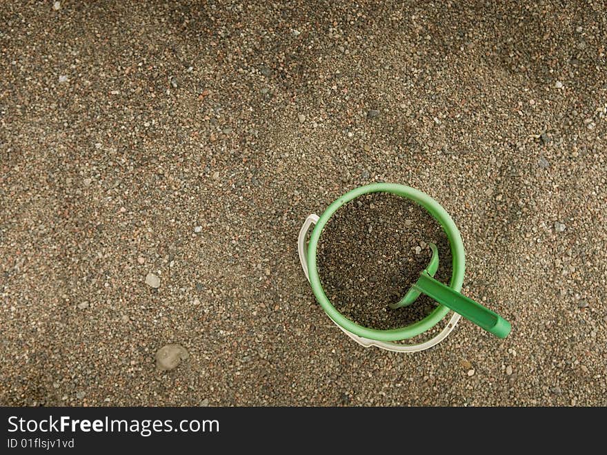 Green sand bucket standing in a sandbox