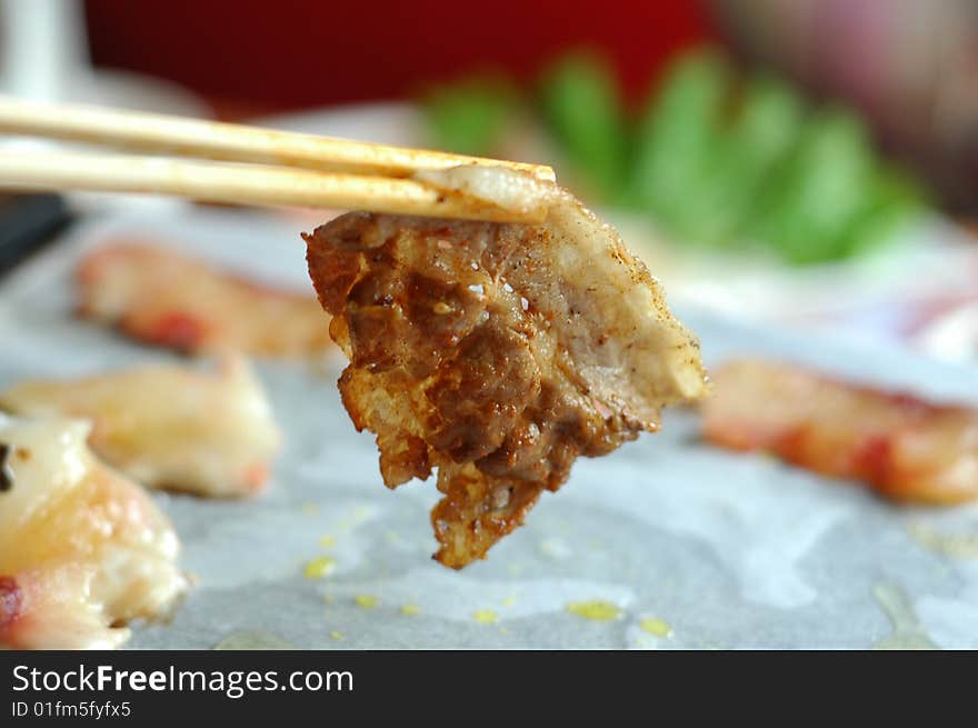 Welldone mutton slice held by chopsticks.