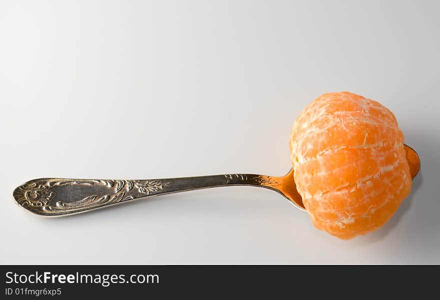 Metal teaspoon holding a half of tangerine from above