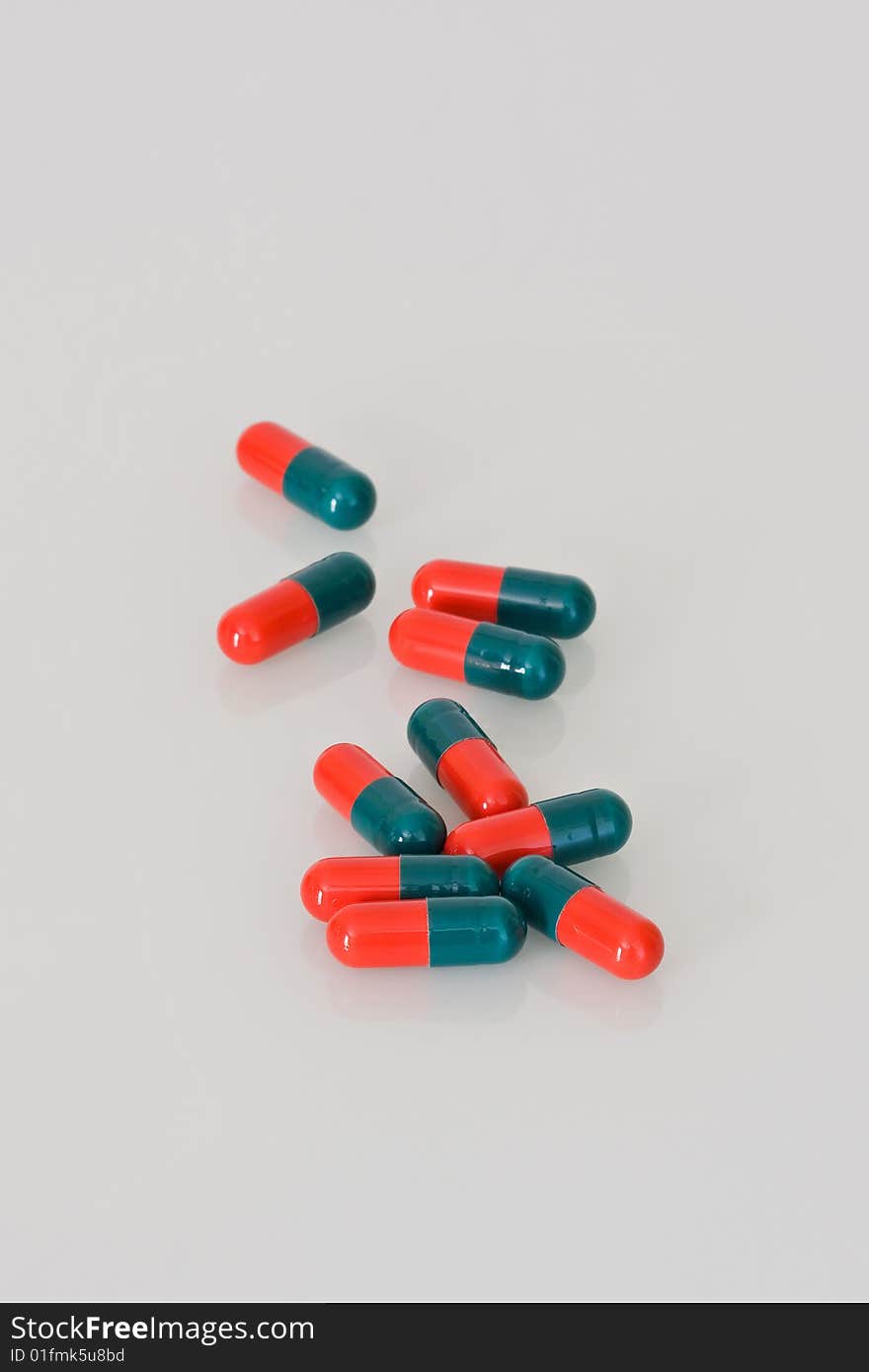 Ten scattered red and green medical capsules