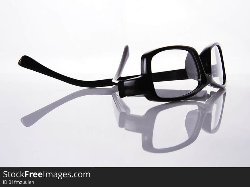 A black frame eyeglasses in plain white background with reflection.