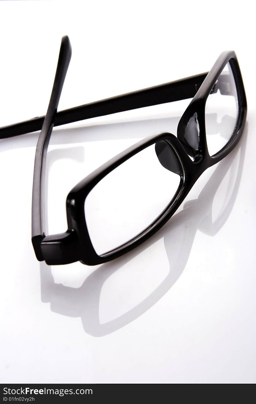 A black frame eyeglasses in plain white background with reflection.