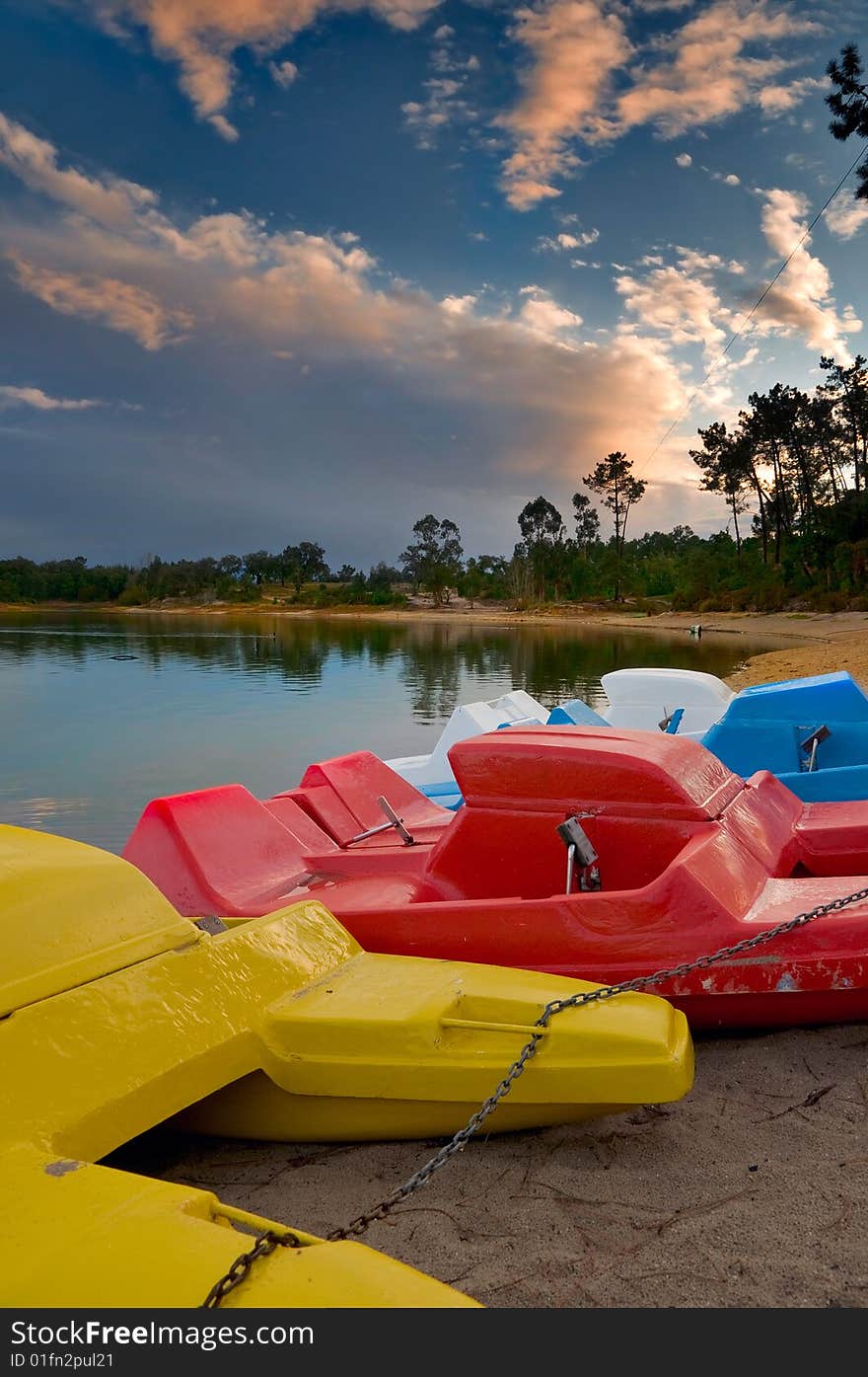 Pedal boats of various colors lined up at lake bank