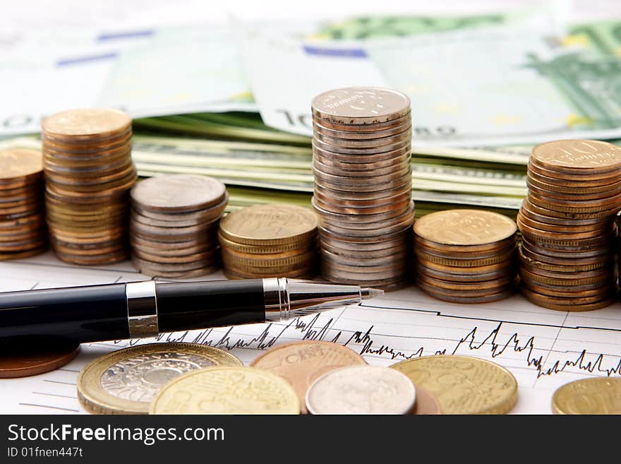 Close up of coins and pen on a graph