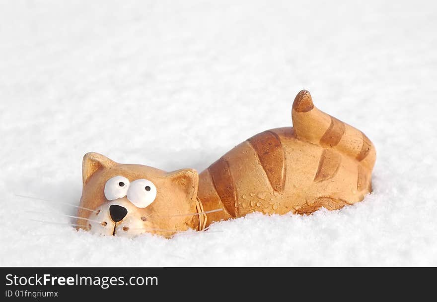 Ceramic toy cat sinking into snow. Ceramic toy cat sinking into snow