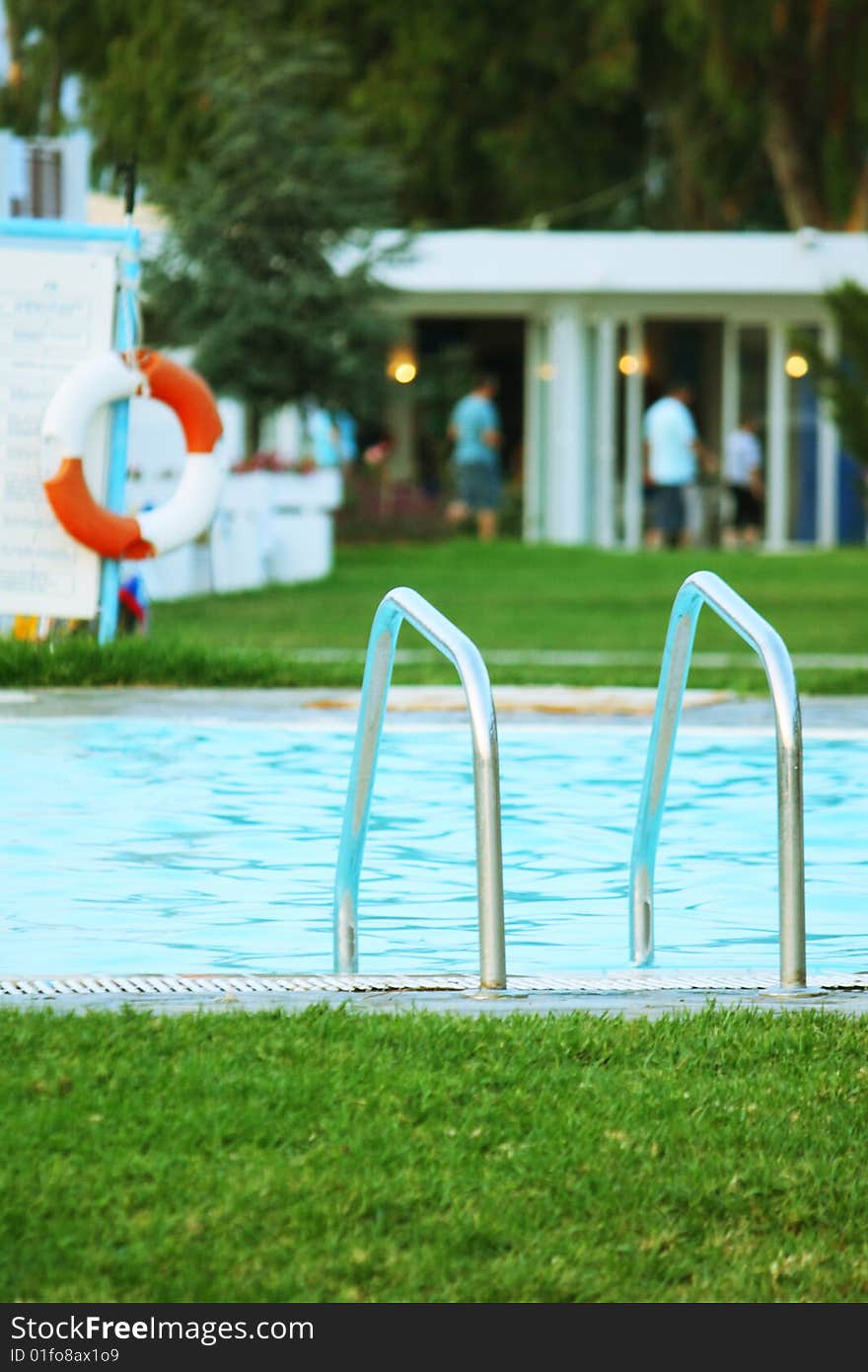 Stair in swimming pool, ring buoy in background