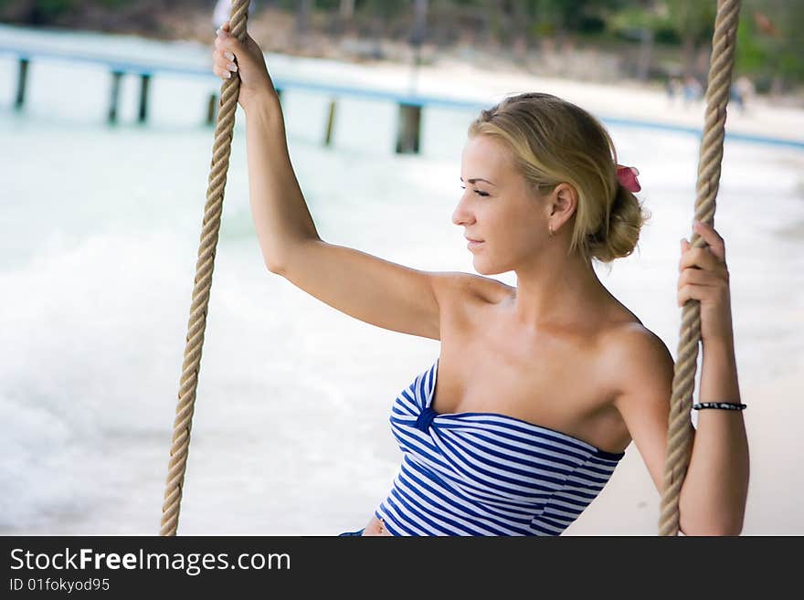 Pretty girl swinging on rope swings on the beach