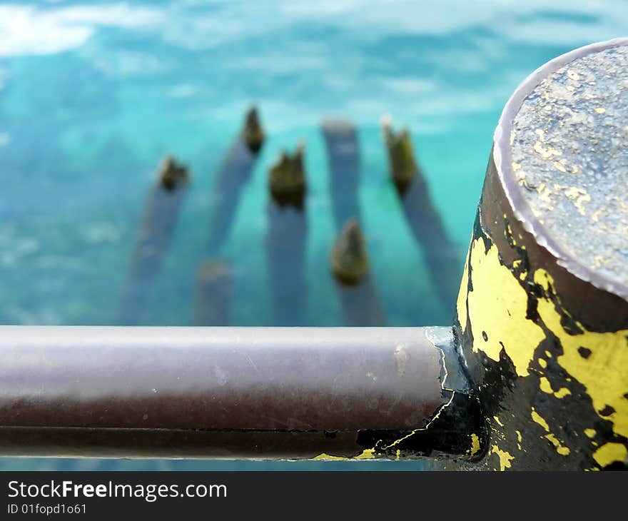 Corroded metal fence and blurred background, wooden posts in water. Corroded metal fence and blurred background, wooden posts in water.