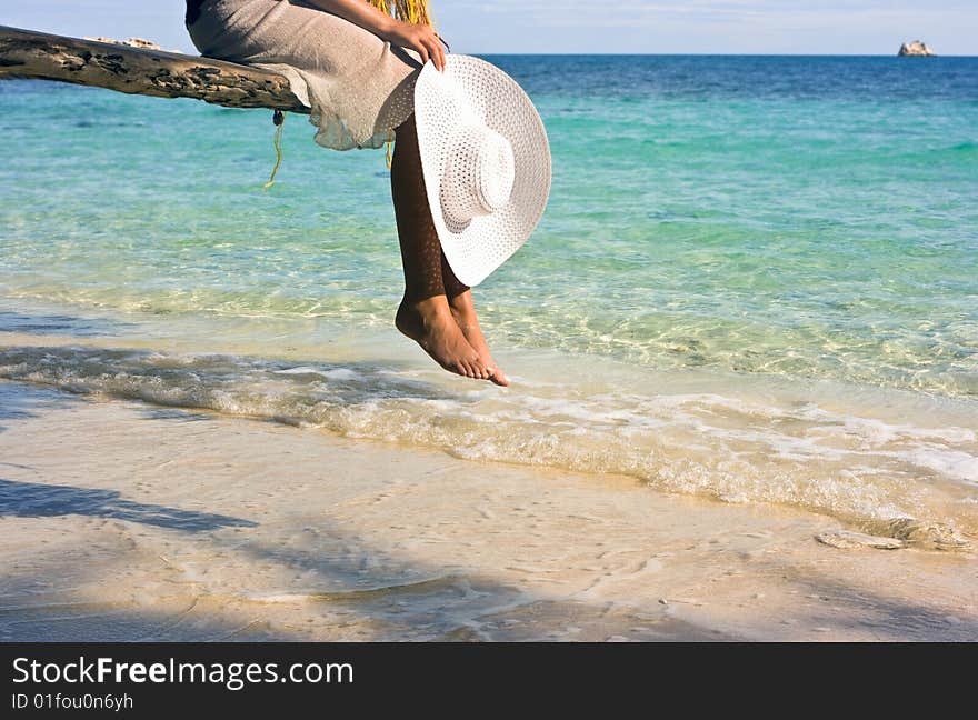 Girl sitting on the beach tree overwhelming the waters. Girl sitting on the beach tree overwhelming the waters