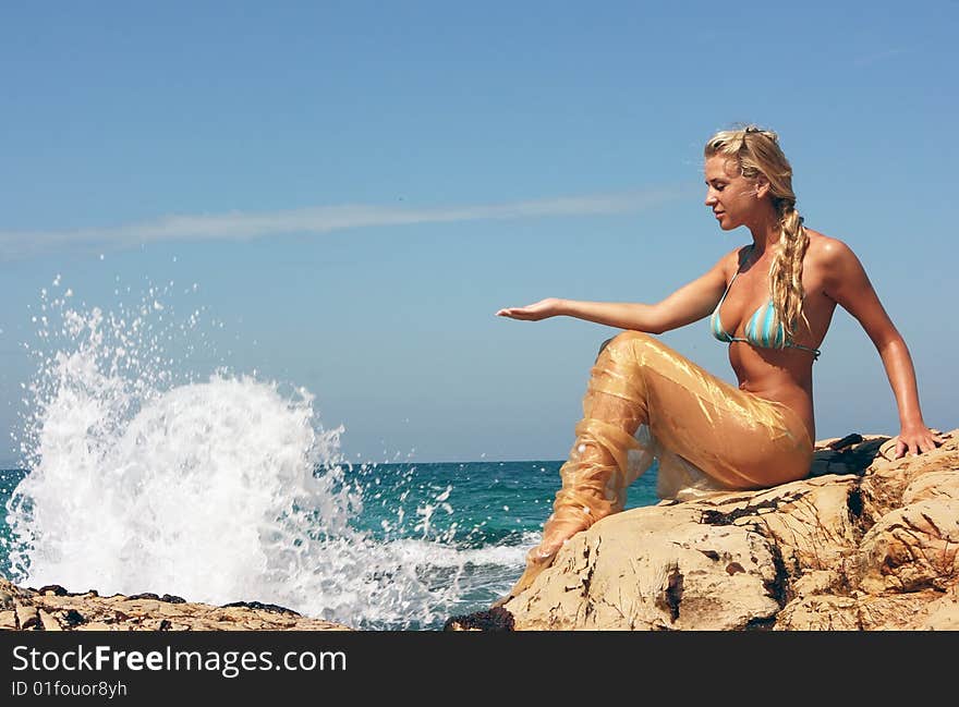 Blond beauty girl sitting on the rocky beach. Blond beauty girl sitting on the rocky beach