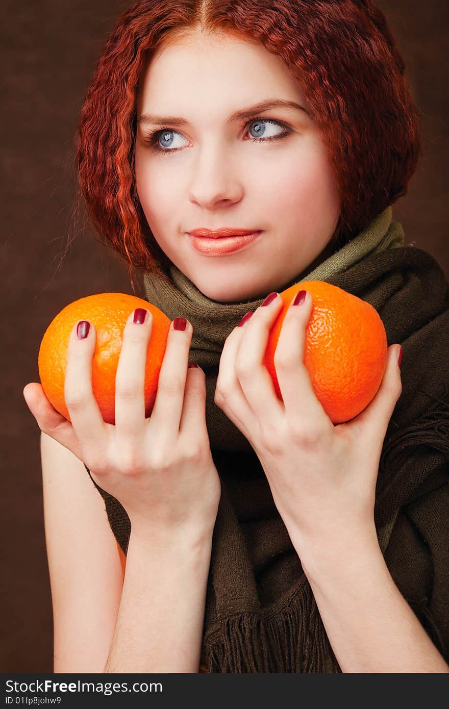 Young pretty girl with two oranges on dark background