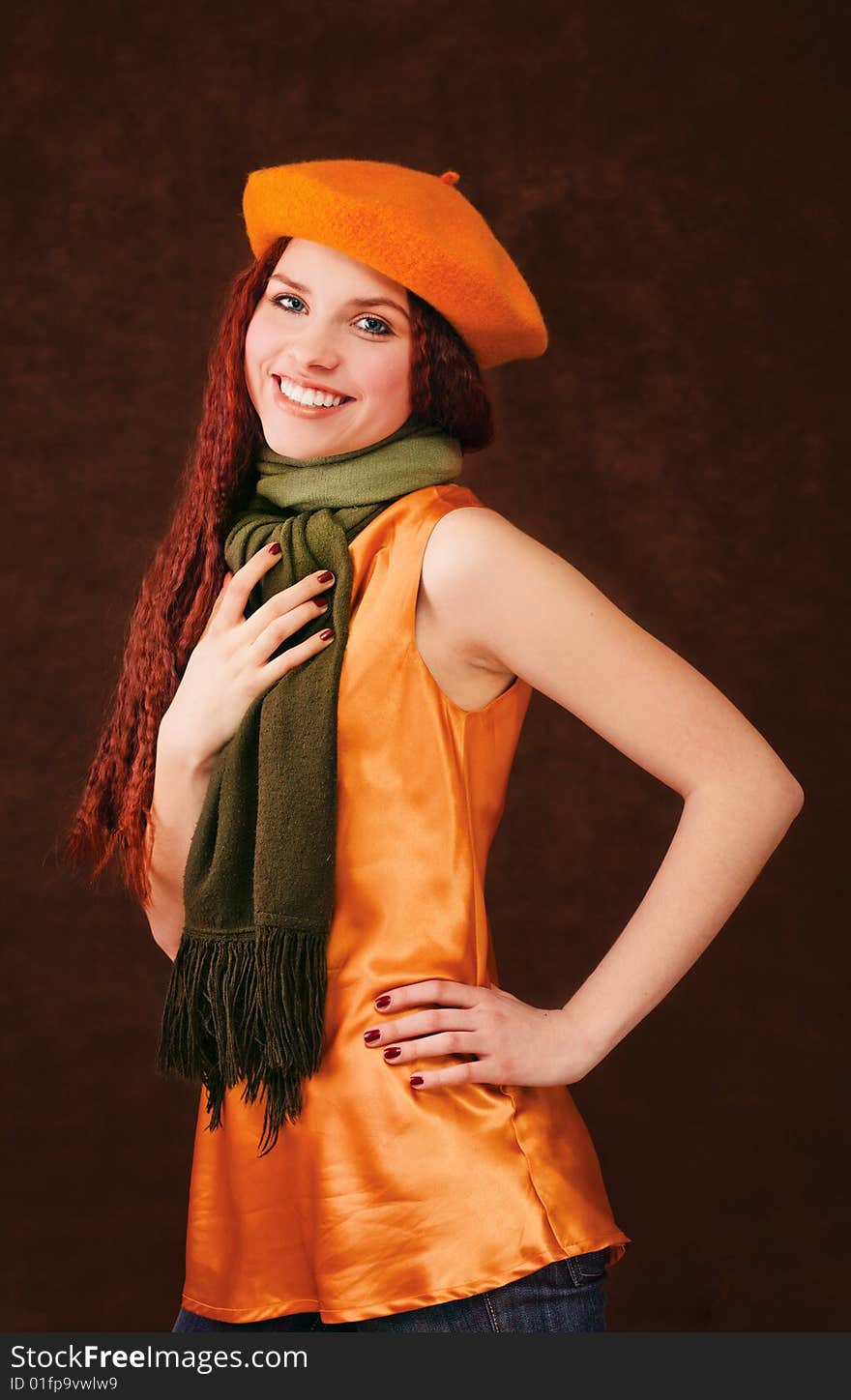 Young beautiful smiling  girl in orange beret on dark background. Young beautiful smiling  girl in orange beret on dark background