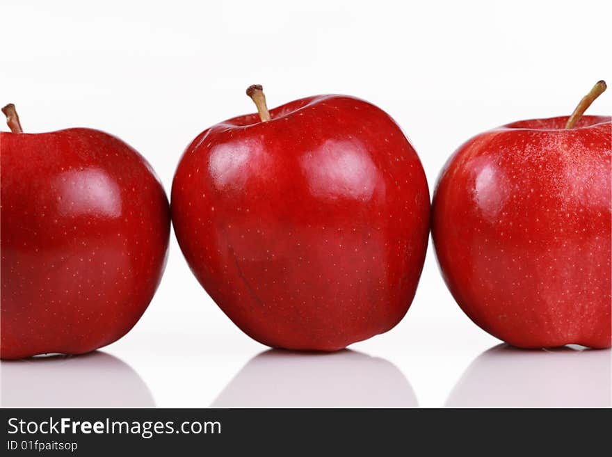 Three shiny red apples in a row isolated on white