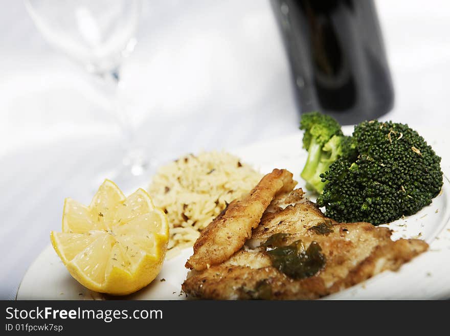 Fish meal with selective focus and wine bootle and glass in the background. Fish meal with selective focus and wine bootle and glass in the background