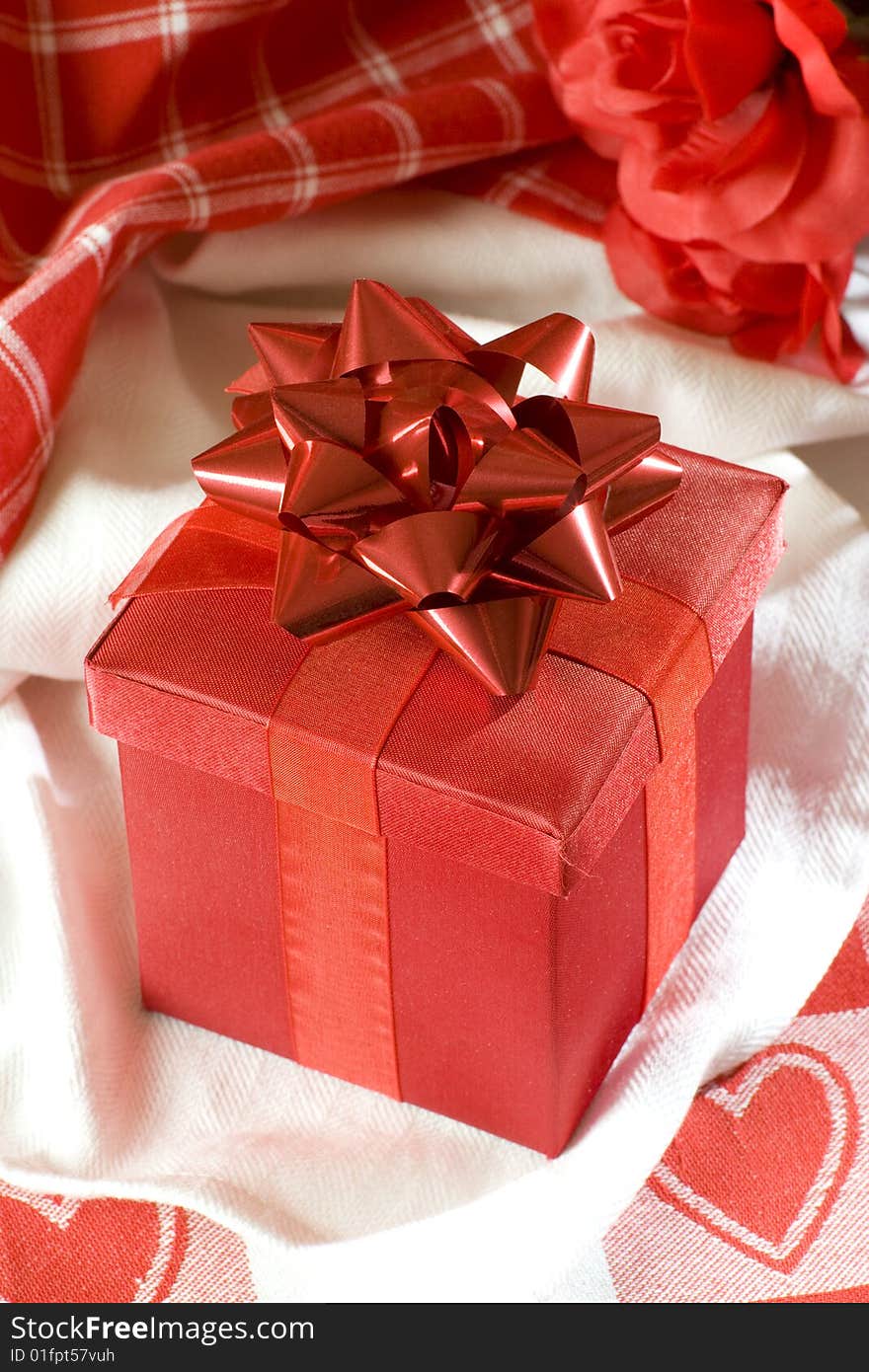 Red Valentines gift box on table cloth with red hearts. Red Valentines gift box on table cloth with red hearts