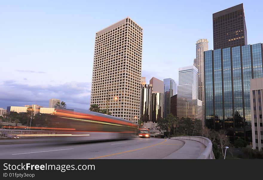 Two buses traveling through Los Angeles just after sunset