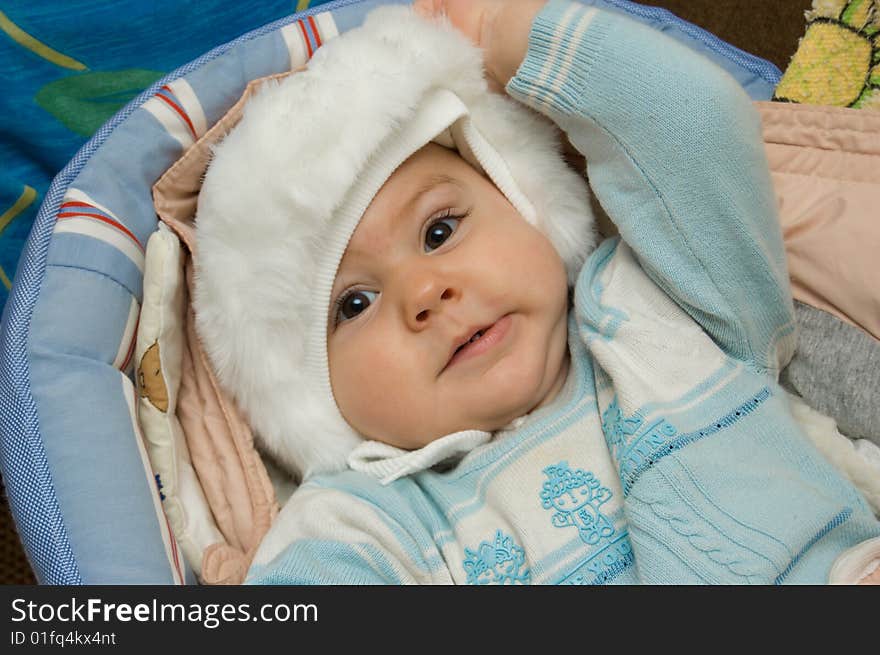 Baby is trying to take off his hat. Baby is trying to take off his hat