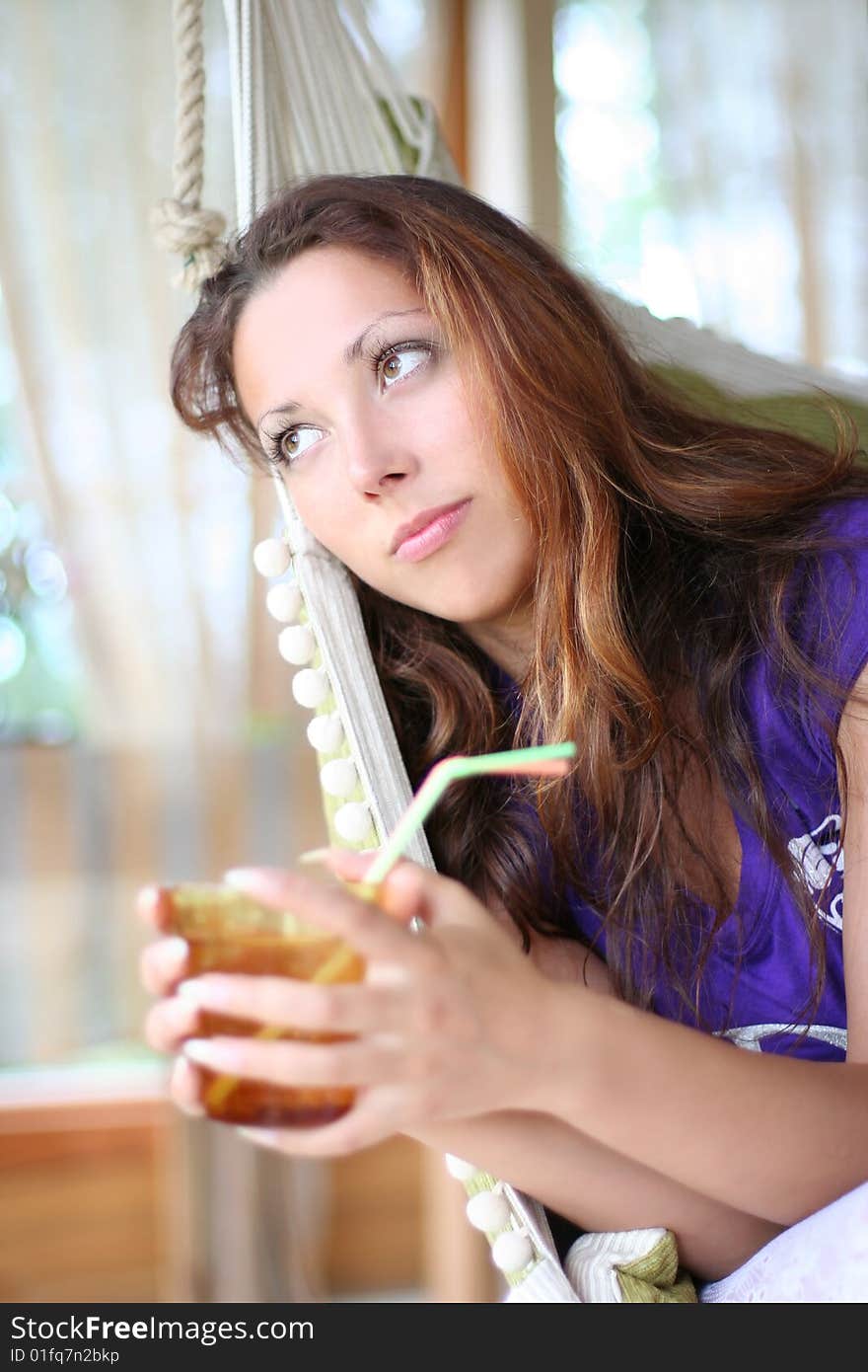 Happy long-haired girl drinking lemonade in comfortable cottage