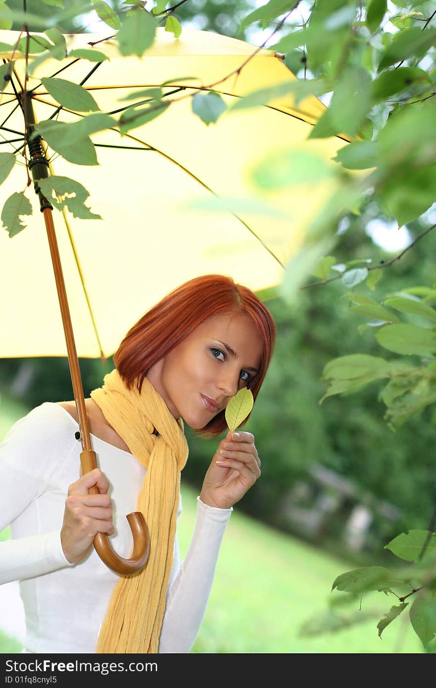 Beautiful young girl under yellow umbrella in the autumn park. Beautiful young girl under yellow umbrella in the autumn park