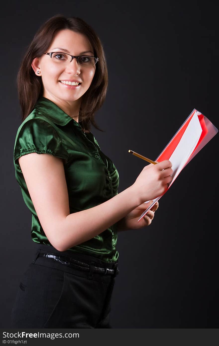 Cheerful young business woman with a red folder against a dark background